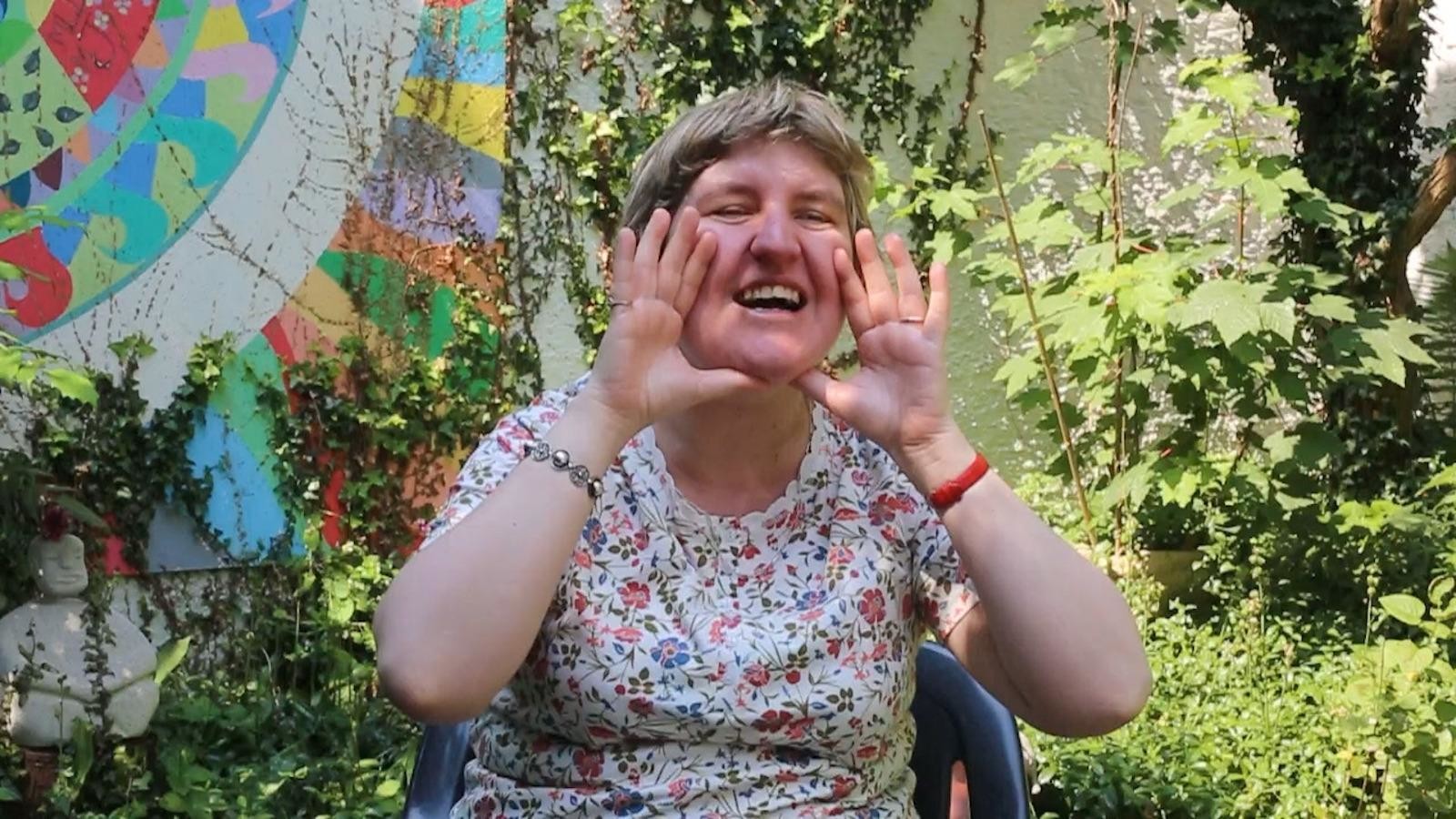 Une intervenante, dans un jardin semble crier quelque chose